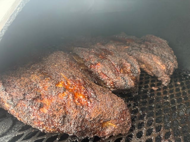 Close view of deeply smoked brisket bark inside the pit.