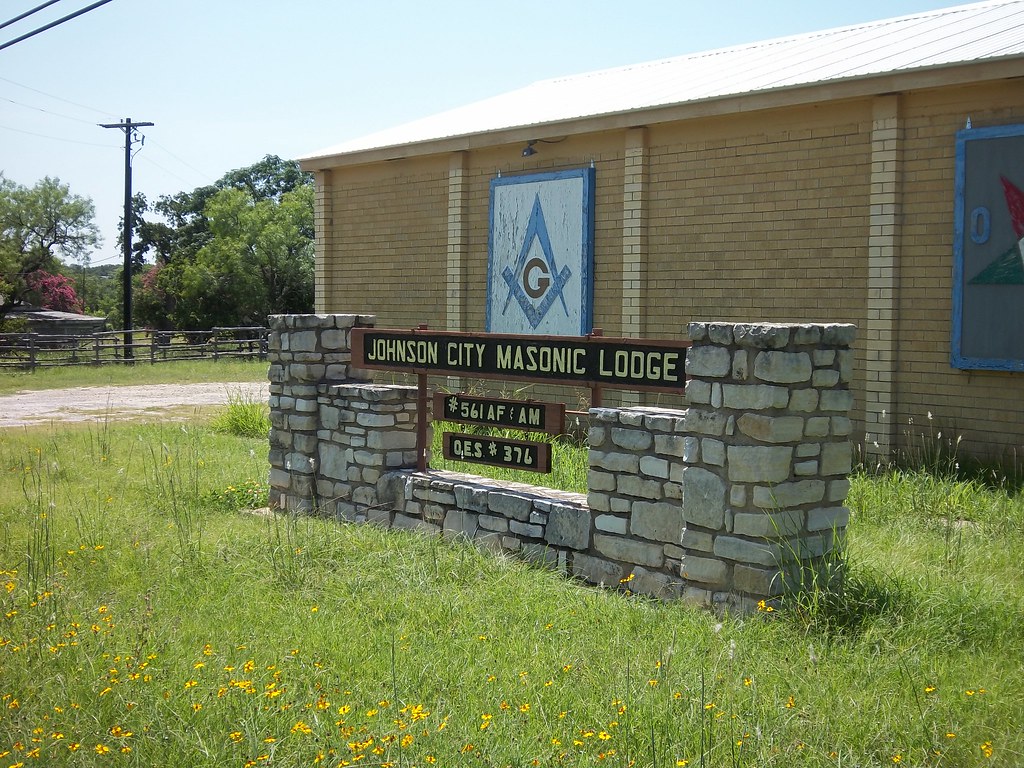 The Johnson City Masonic Lodge building on US-290 West, with its stone monument sign and the painted square and compass on the facade.