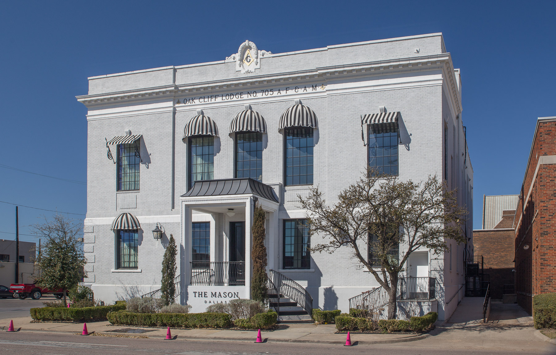 The Oak Cliff Masonic Lodge building in Dallas, a two-story white brick temple with OAK CLIFF LODGE NO. 705 A.F. & A.M. carved across the facade and a square-and-compasses medallion at the parapet.