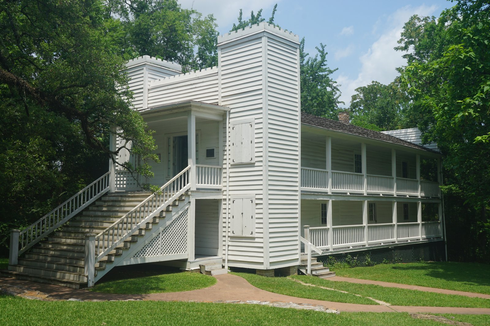 The Steamboat House in Huntsville, Texas, a narrow two-story white frame house with twin towers and long side galleries, photographed in 2022.