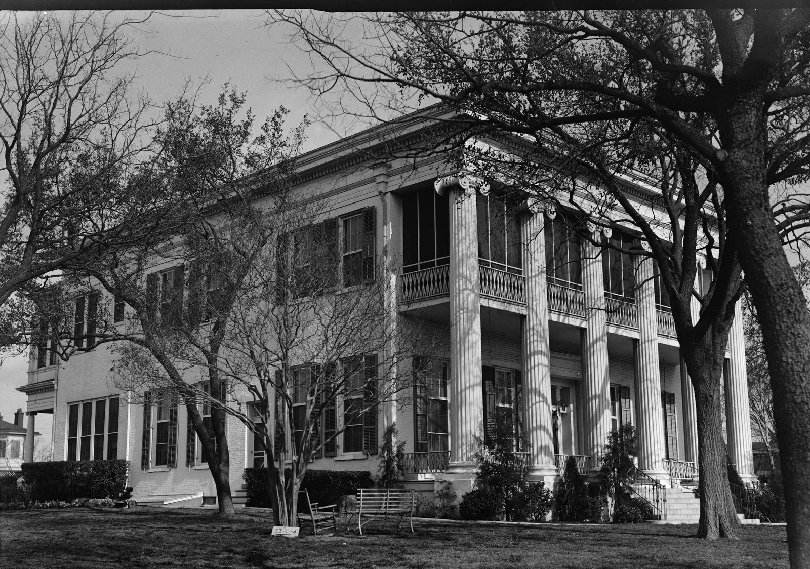 The Texas Governor's Mansion in Austin, a two-story Greek Revival house with tall Ionic columns and an iron-railed balcony, photographed at an angle through winter trees for the Historic American Buildings Survey.