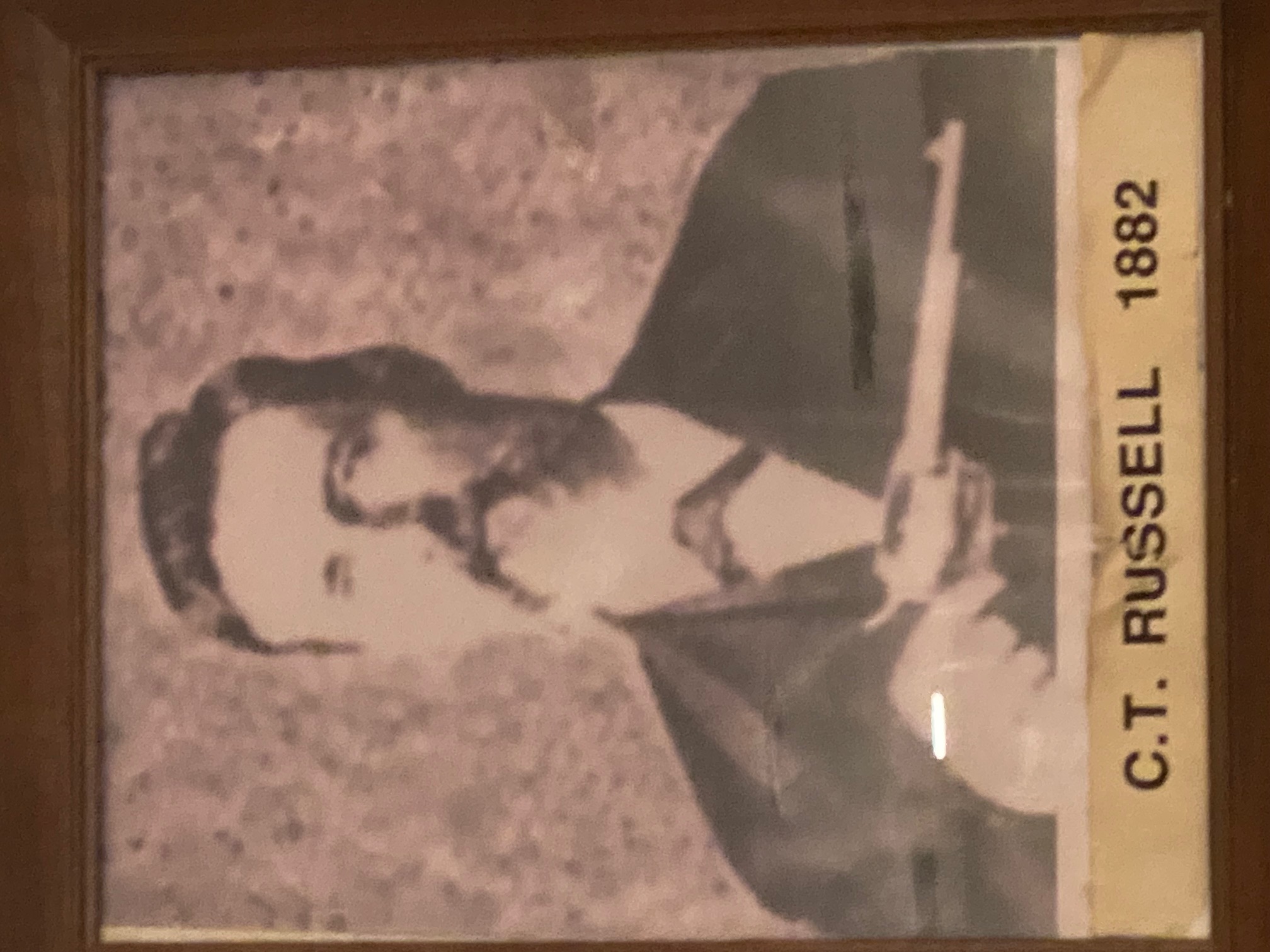 C.T. Russell, 1882. Sepia portrait of the Worshipful Master holding a pistol — the founding spirit of Johnson City Lodge No. 561.